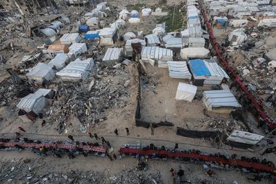 Palestinians gather among destroyed buildings to break their fast together during the holy month of Ramadan in Jabalia camp, northern Gaza Strip-stock-foto
