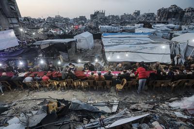 Palestinians gather among destroyed buildings to break their fast together during the holy month of Ramadan in Jabalia camp, northern Gaza Strip-stock-foto