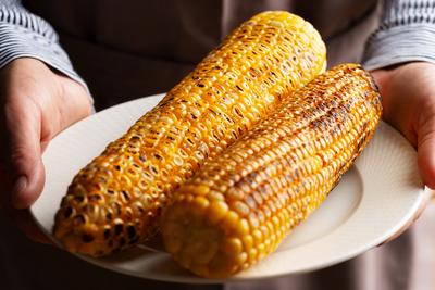 Caucasian male hands holds plate with grilled sweetcorn Caucasian male hands holds plate with grilled sweetcorn Copyrigh-stock-photo