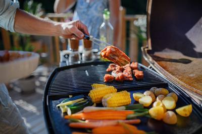 Unrecognizable man grilling ribs and vegetable on grill during family summer garden party, close-up An unrecognizable ma-stock-foto