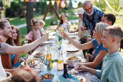 Family clinking glasses at summer garden party. Celebratory toast at the table. Family and friends clinking glasses at s-stock-foto