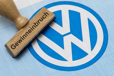 Gewinneinbruch bei VW Volkswagen Ein Holzstempel mit dem Aufdruck Gewinneinbruch liegt auf einer Aktie der Volkswagen AG-stock-foto