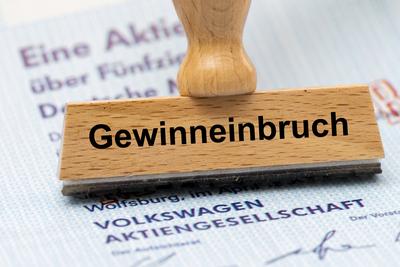 Gewinneinbruch bei VW Volkswagen Ein Holzstempel mit dem Aufdruck Gewinneinbruch liegt auf einer Aktie der Volkswagen AG-stock-foto