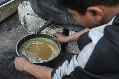 Palestinian workers pours out processed fuel from recycled plastic in Gaza City-stock-foto