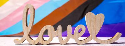 Banner Wooden word love with heart romance on Rainbow LGBTQIA flag made from silk material. Valentine s Day greeting car-stock-photo