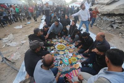Palestinians break their fast at a table set amidst the destruction and debris caused by Israeli attacks-stock-foto