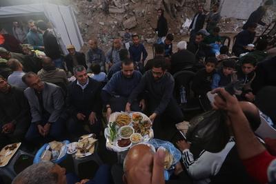 Palestinians break their fast at a table set amidst the destruction and debris caused by Israeli attacks-stock-foto