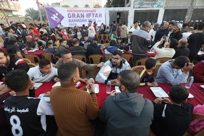 Palestinians break their fast at a table set amidst the destruction and debris caused by Israeli attacks during a mass iftar program in Nusairat in central of Gaza Strip-stock-foto