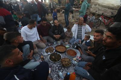 Palestinians break their fast at a table set amidst the destruction and debris caused by Israeli attacks-stock-foto