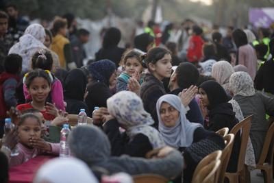 Palestinians break their fast at a table set amidst the destruction and debris caused by Israeli attacks during a mass iftar program in Nusairat in central of Gaza Strip-stock-foto