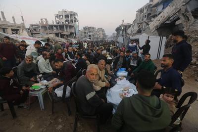 Palestinians break their fast at a table set amidst the destruction and debris caused by Israeli attacks-stock-foto