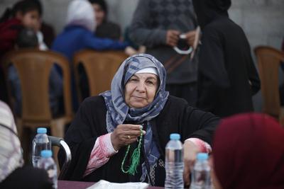 Palestinians break their fast at a table set amidst the destruction and debris caused by Israeli attacks during a mass iftar program in Nusairat in central of Gaza Strip-stock-foto