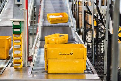 Germering, Bavaria, Germany - 18 March 2025: Yellow Deutsche Post mailboxes travel along a conveyor belt at the mail cen-stock-foto