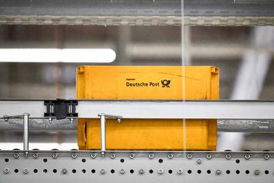 Germering, Bavaria, Germany - 18 March 2025: Deutsche Post s yellow letter boxes move on an automated conveyor belt in a-stock-foto