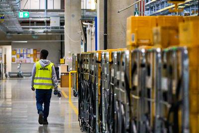 Germering, Bavaria, Germany - 18 March 2025: A DHL employee in a high-visibility vest walks through the Deutsche Post ma-stock-foto