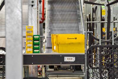 Germering, Bavaria, Germany - 18 March 2025: Yellow Deutsche Post mailboxes travel along a conveyor belt at the mail cen-stock-foto