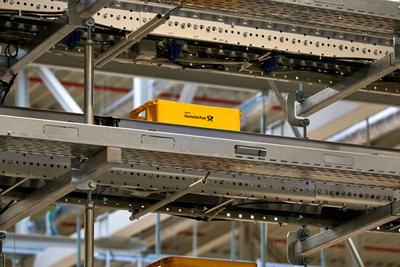 Germering, Bavaria, Germany - 18 March 2025: Deutsche Post s yellow letter boxes move on an automated conveyor belt in a-stock-foto