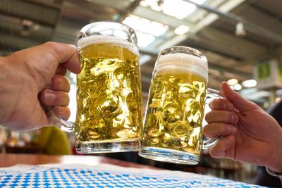 Augsburg, Bavaria, Germany - March 7, 2025: Two men clink glasses with full mugs of beer. The glasses are filled with go-stock-foto