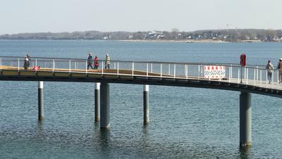 Touristen gehen am Donnerstagnachmittag bei Temperaturen ?ber 15 Grad und Windstille ?ber die Maritim Seebr?cke Timmendo-stock-foto