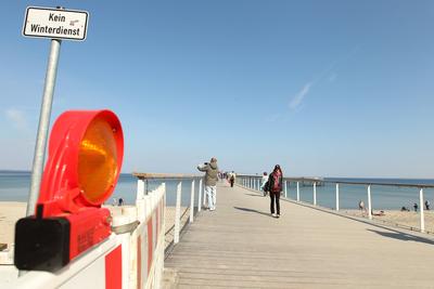 Touristen gehen am Donnerstagnachmittag bei Temperaturen ?ber 15 Grad und Windstille ?ber die Maritim Seebr?cke Timmendo-stock-foto