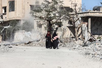 Displaced Palestinians continue to return their houses past heavily damaged and partially collapsed buildings after the ceasefire and hostage-prisoner swap deal between Hamas and Israel at Bureij-stock-foto