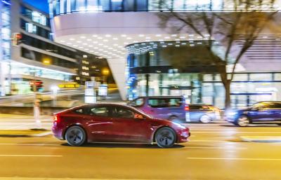 Tesla bei Nacht vor urbaner Umgebung mit moderner Architektur, Mitzieher. // 03.02.2025: Stuttgart, Baden-W?rttemberg, D-stock-foto