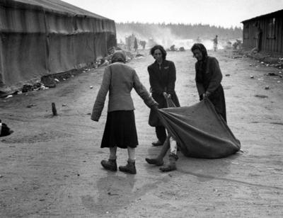 Bergen-Belsen Concentration Camp. Inmates drag diseased body using a blanket after the camp has been turned over to the-stock-photo