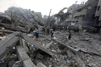 Palestinians try to salvage some items in the devastated yard of a schoo-stock-foto