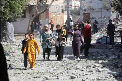 Palestinians try to salvage some items in the devastated yard of a schoo-stock-foto