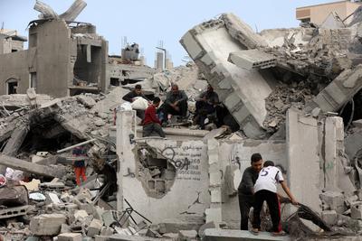 Palestinians try to salvage some items in the devastated yard of a schoo-stock-foto