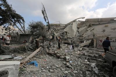 Palestinians try to salvage some items in the devastated yard of a schoo-stock-foto
