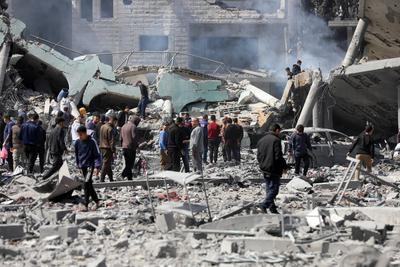 Palestinians try to salvage some items in the devastated yard of a schoo-stock-foto