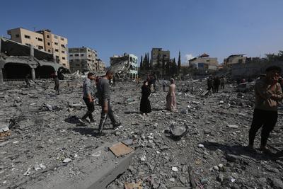Palestinians try to salvage some items in the devastated yard of a schoo-stock-foto