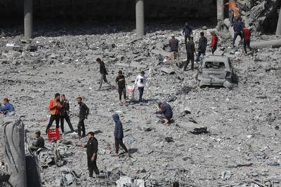 Palestinians try to salvage some items in the devastated yard of a schoo-stock-foto