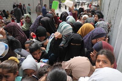 Palestinians, including women and children, scramble to collect food during a distribution by the charity organization-stock-photo