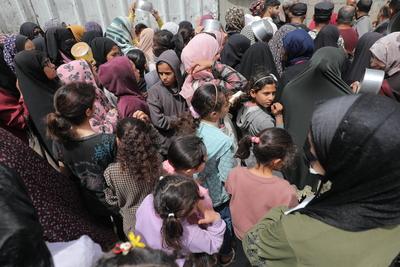 Palestinians, including women and children, scramble to collect food during a distribution by the charity organization-stock-photo
