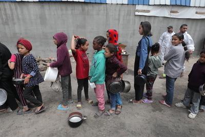 Palestinians, including women and children, scramble to collect food during a distribution by the charity organization-stock-photo