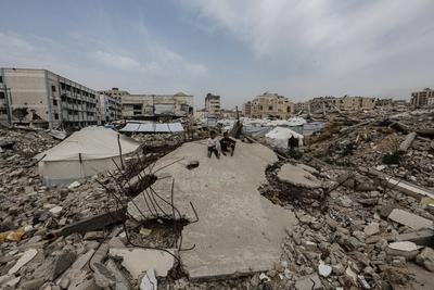 Palestinians try to go about their daily lives amid the rubble of buildings or their makeshift tents-stock-foto