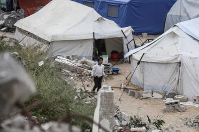 Palestinians try to go about their daily lives amid the rubble of buildings or their makeshift tents-stock-foto