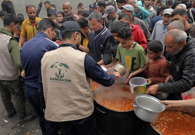 Palestinians gather in large numbers to receive the meals distributed by charities in the Nuseirat refugee camp, in the central part of Gaza-stock-photo