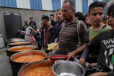 Palestinians gather in large numbers to receive the meals distributed by charities in the Nuseirat refugee camp, in the central part of Gaza-stock-photo