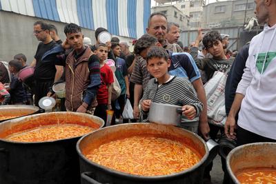 Palestinians gather in large numbers to receive the meals distributed by charities in the Nuseirat refugee camp, in the central part of Gaza-stock-photo