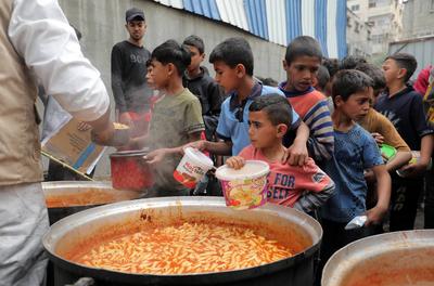 Palestinians gather in large numbers to receive the meals distributed by charities in the Nuseirat refugee camp, in the central part of Gaza-stock-photo