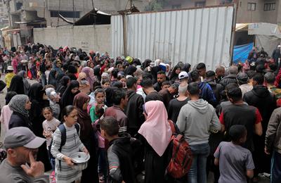 Palestinians gather in large numbers to receive the meals distributed by charities in the Nuseirat refugee camp, in the central part of Gaza-stock-photo