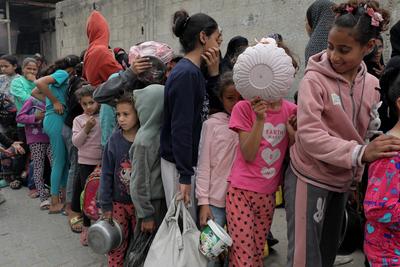 Palestinians gather in large numbers to receive the meals distributed by charities in the Nuseirat refugee camp, in the central part of Gaza-stock-photo