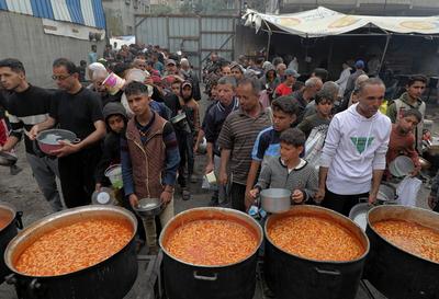 Palestinians gather in large numbers to receive the meals distributed by charities in the Nuseirat refugee camp, in the central part of Gaza-stock-photo