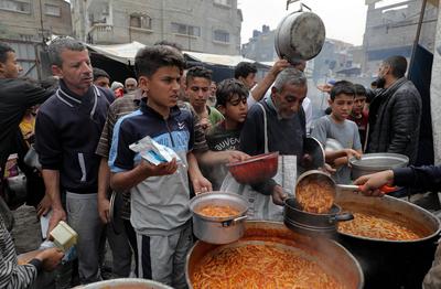 Palestinians gather in large numbers to receive the meals distributed by charities in the Nuseirat refugee camp, in the central part of Gaza-stock-photo