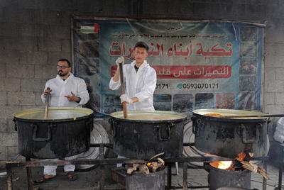 Palestinians gather in large numbers to receive the meals distributed by charities in the Nuseirat refugee camp, in the central part of Gaza-stock-photo