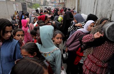 Palestinians gather in large numbers to receive the meals distributed by charities in the Nuseirat refugee camp, in the central part of Gaza-stock-photo