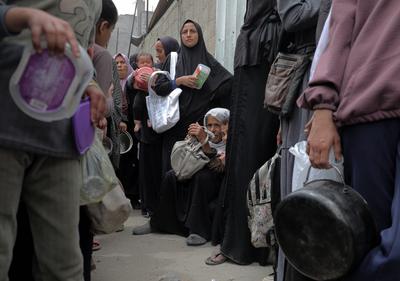 Palestinians gather in large numbers to receive the meals distributed by charities in the Nuseirat refugee camp, in the central part of Gaza-stock-photo